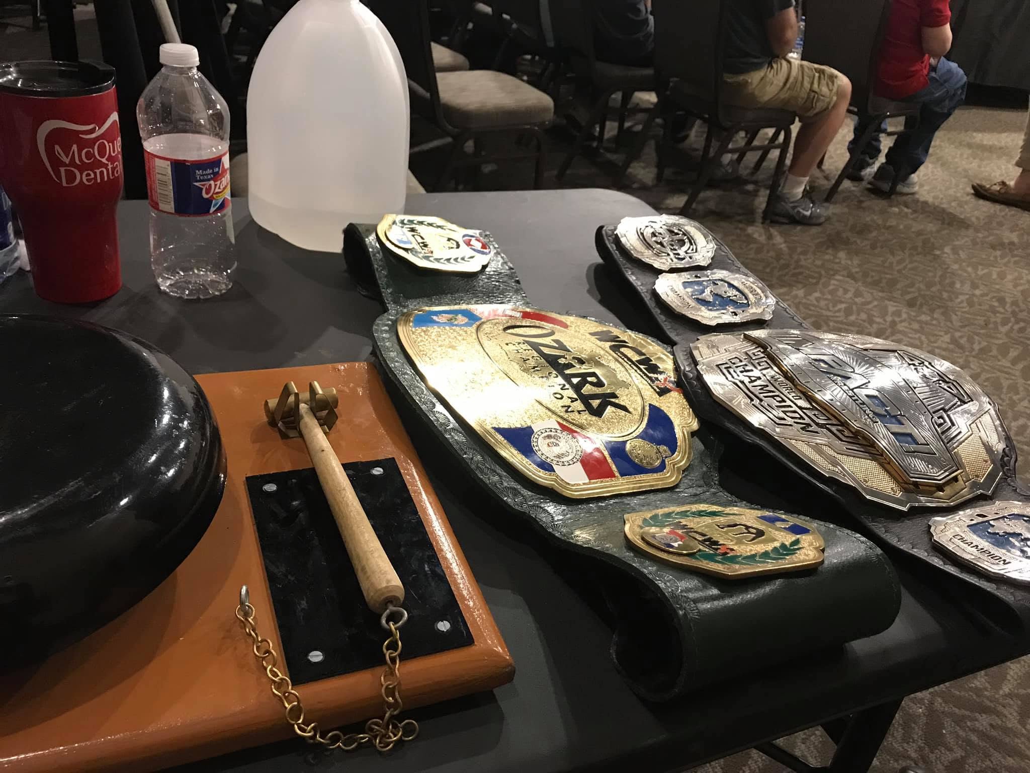 The WCWA Ozark Championship and IMPACT World Championship belts beside the ring bell at Monsters and Men in October 2019.